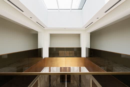 Villa Dubai Hills: a skylit stairwell lined in bronze glass and timber