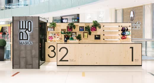 Maska Wraps kiosk in Dubai Mall: a pine counter numbered 1, 2, 3 and a dark stone tower